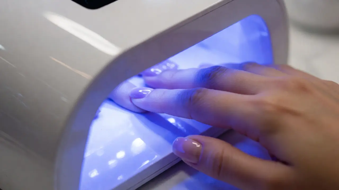 Ruka v UV lampě při vytvrzování gelového laku na nehtech